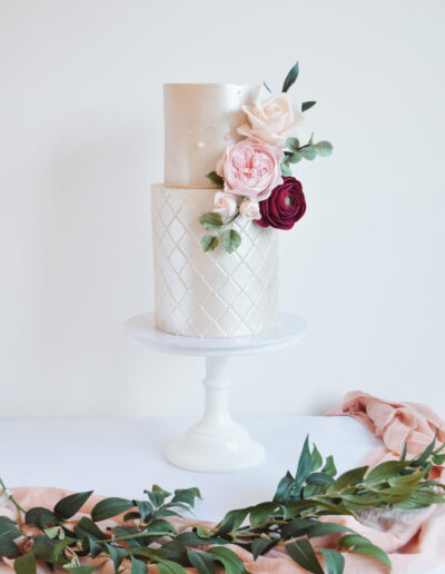 Luxury Wedding Cake - Two tier wedding cake. Extended base tier with quilting effect. Lustred finished cake dressed with hancrafted sugar blooms