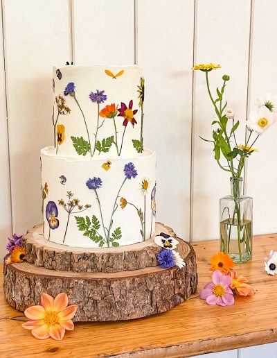 Full buttercream two tier wedding cake - dressed with edible pressed organic wild flower blooms.